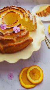 orange bundt cake on a cake holder with orange slices